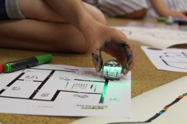 CMT2020_ProgrammierenLernenMitDenOzobots_IMG_6622 Zu sehen ist ein Kind, das mit großem Vorlagenbogen, Roboter und Stiften arbeitet.