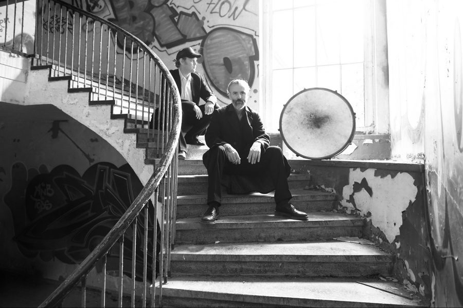 Zu sehen sind die Bandmitglieder der Albinorothers auf Stufen in einem Treppenhaus sitzend, neben ihnen eine Bass Drum