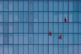 3 Fensterputzer an einem Seil, putzen die Glasfassade eines Hochhauses