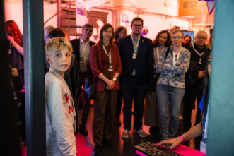 zwei Kinder präsentieren ein Werk, Publikum schaut zu.