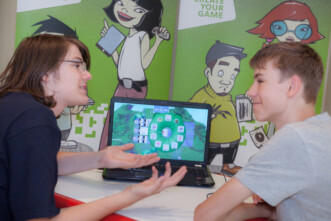 Zwei Jugendliche besprechen Computerspiel vor Laptop