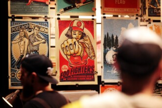 Blick auf die Posterausstellung mit einigen Siebdruckpostern. Im Vordergrund sind unscharf zwei Menschen von hinten zu sehen.